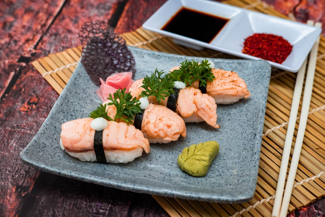 a plate of sushi with chopsticks and sauce