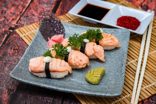 a plate of sushi with chopsticks and sauce
