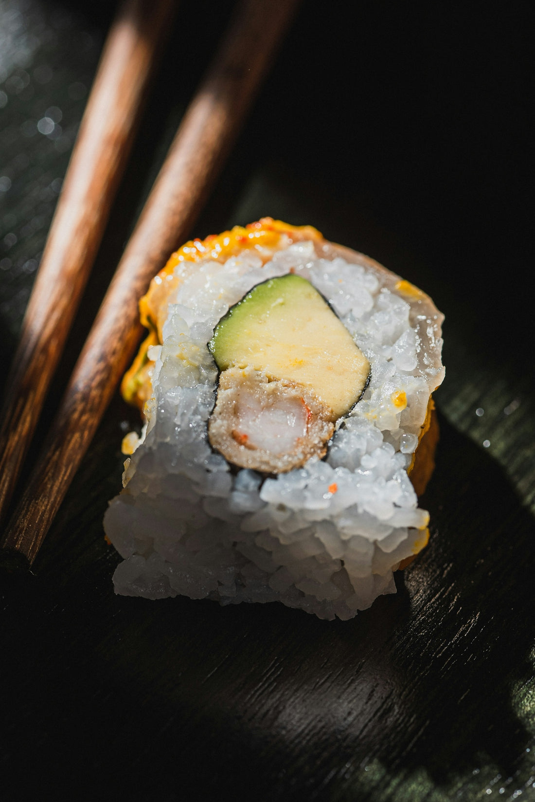 A single piece of sushi with avocado and shrimp.