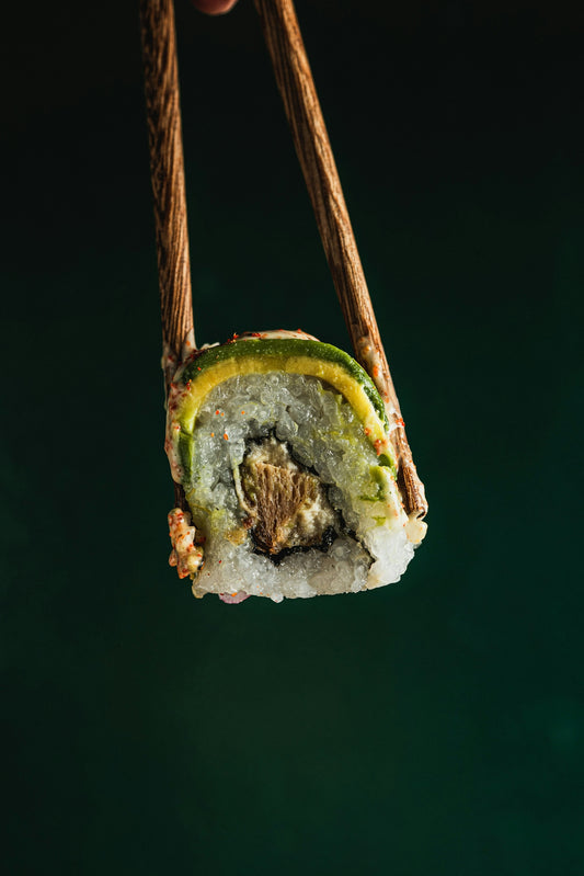 Chopsticks holding a single piece of sushi roll.