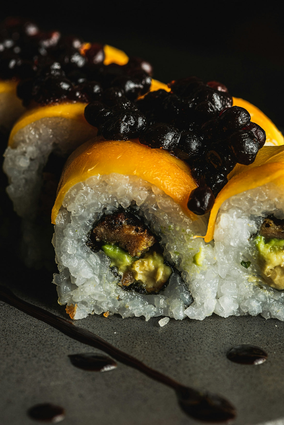 Sushi rolls topped with mango and dark caviar.