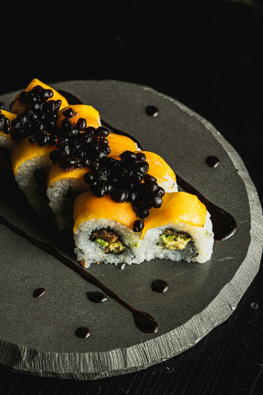 Sushi rolls topped with mango and black caviar