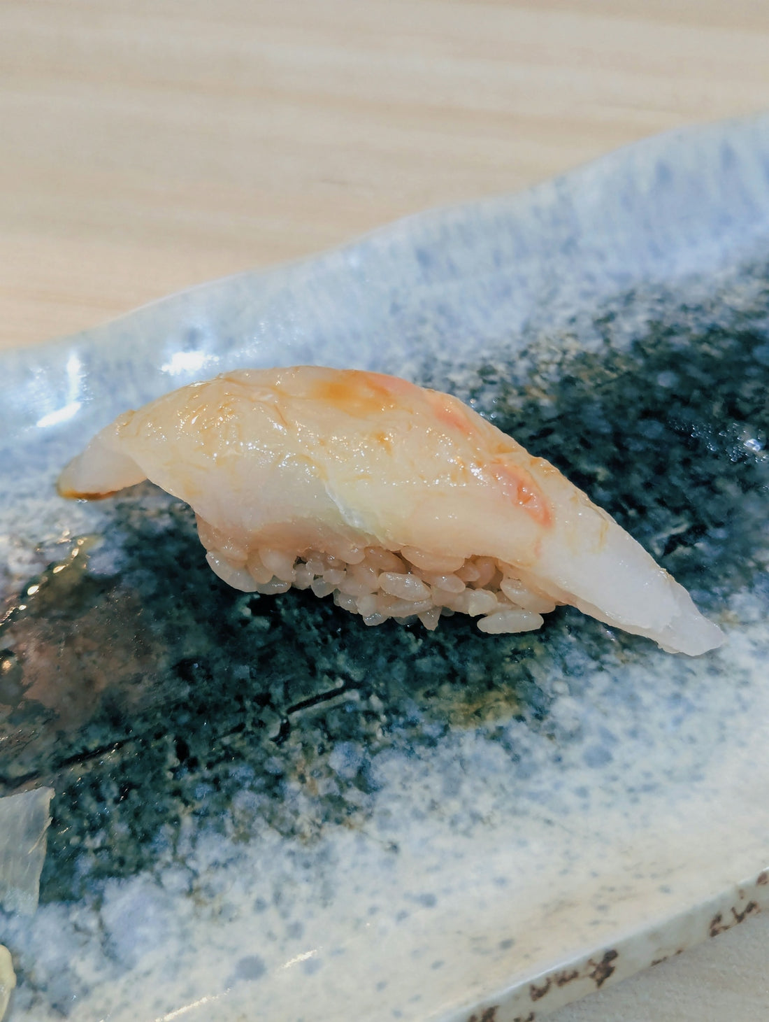 A single piece of white fish sushi on a plate
